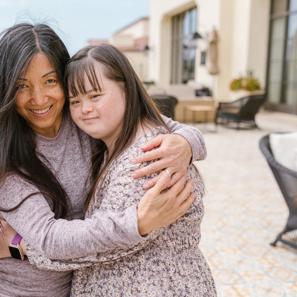 Two friends embracing and laughing together outdoors