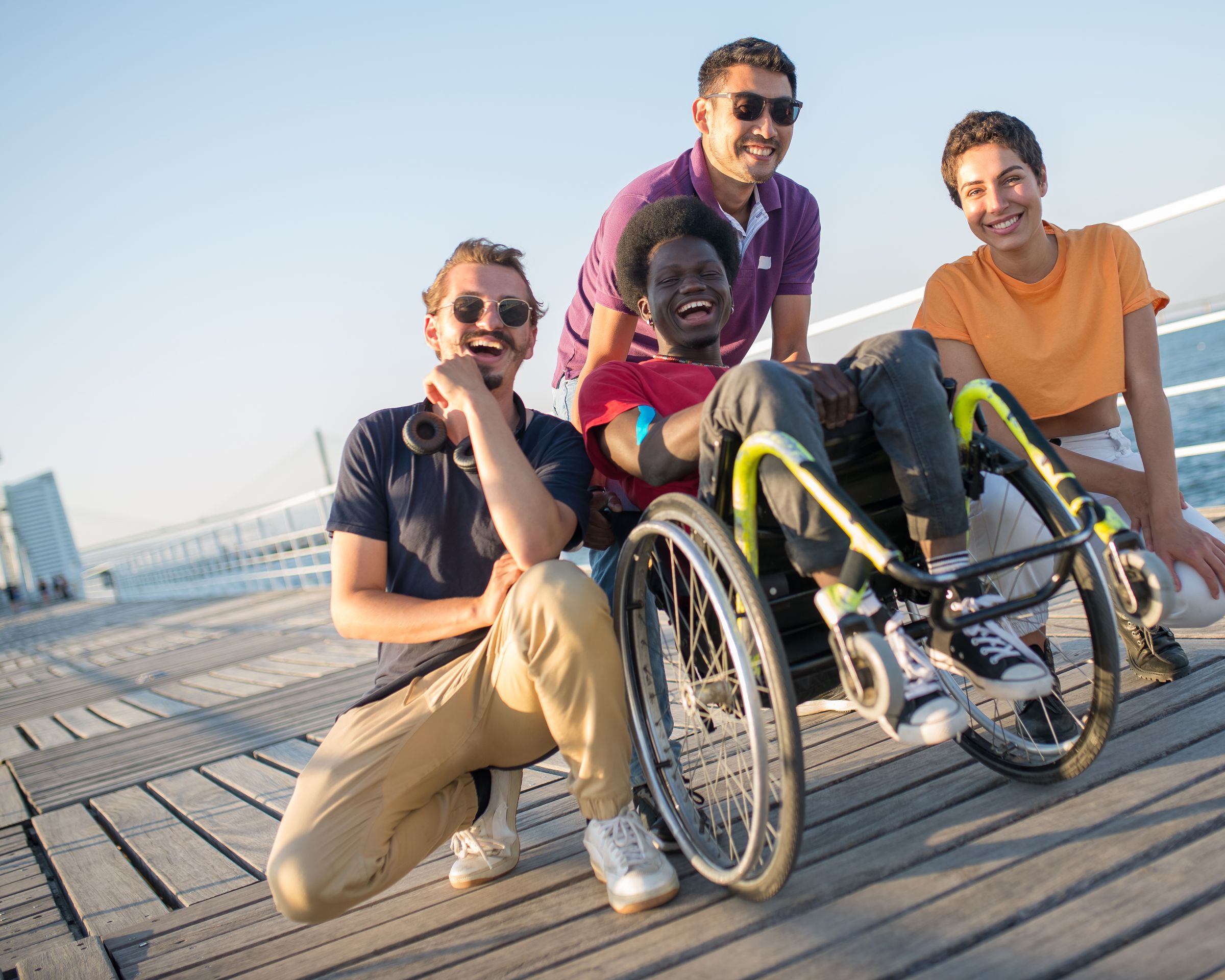 A group of friends, including a wheelchair user, smiling together outdoors